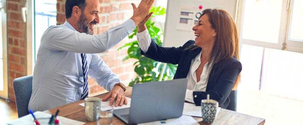 Man and woman giving each other a high five after completing their SAM renewal paperwork