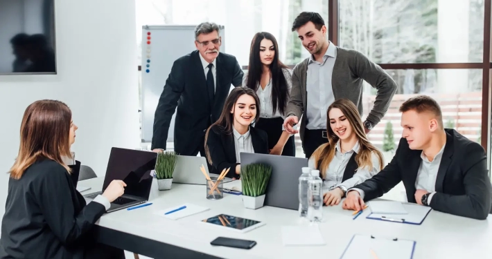 Four women and three men gathered around a table looking at their new government contracts