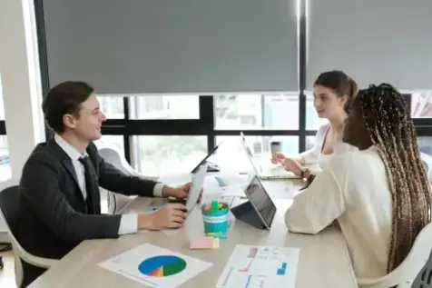 Man and two women sitting at a conference table discussing company capability statements for a client's minority owned business